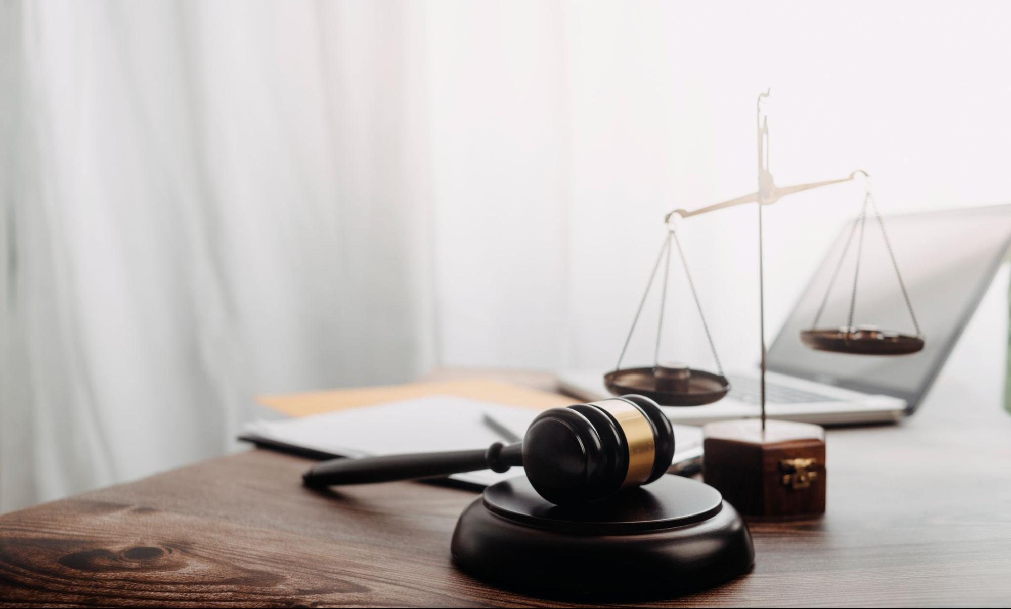 An attorney's desk with a scale, gavel, and laptop